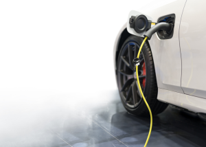 A smoking electric vehicle plugged in inside a home garage, symbolizing a potential EV battery fire and the insurance questions it raises.